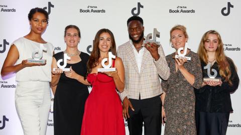 The seven award winners stand in front of a 'TikTok Book Awards' background