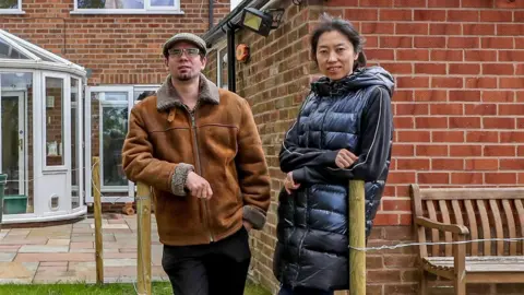 PA Media Matt Raw and his partner Ying at home in Knutsford, Cheshire