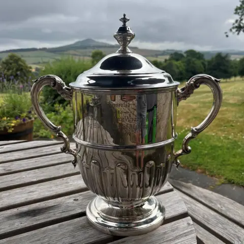 Police Scotland A silver trophy with two ornate handles sitting on a wooden table.