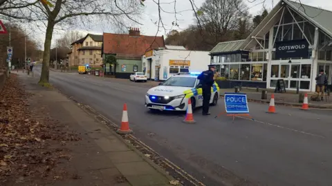 Laura Devlin/BBC A street view image of a police car parked in the middle with a blue police sign 