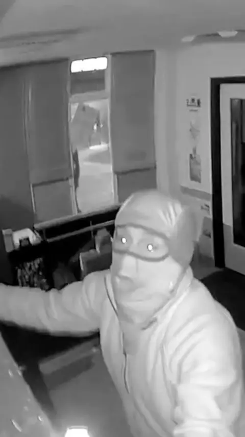 CCTV footage shows a man taking stock from a trading cards shop during raid