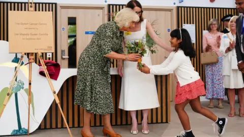 PA Media A child walks towards the Queen with a bouquet of flowers as they stand next to the newly unveiled plaque