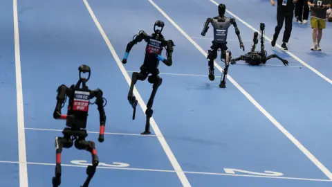 Reuters Humanoid robots compete in a running race as one falls over