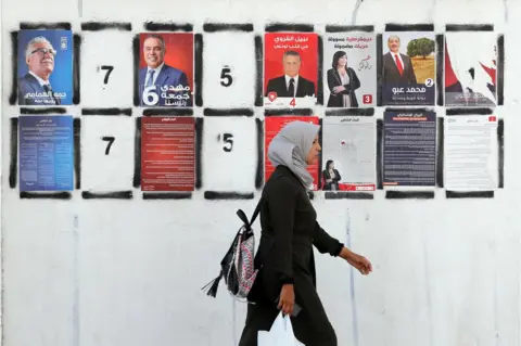 EPA A Tunisian woman walks past posters of Tunisian presidential candidates during presidential campaign in Tunis, Tunisia, 06 September 2019