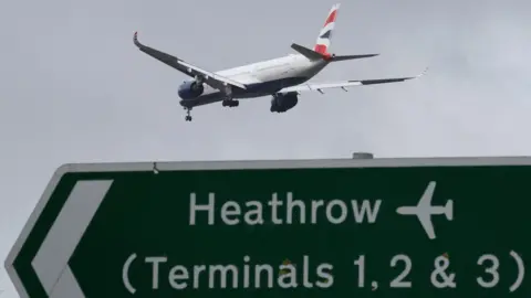 Reuters A British Airways plane flying over a sign thats says "Heathrow (Terminals 1, 2 & 3)