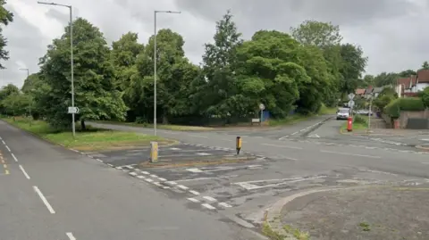 A treelined dual carriageway junction with two side roads.