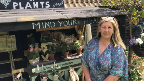BBC/John Devine Leah Francombe stands in front of her roadside flower stall