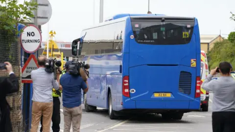 PA Media A coach believed to be carrying asylum seekers arriving at Portland Port in Dorset