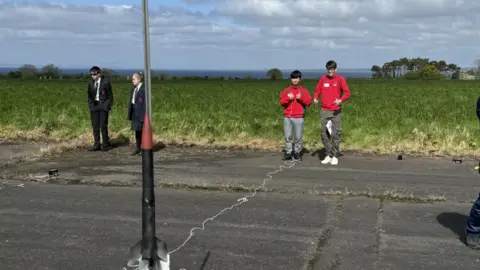 BBC Pupils stand in an airfield preparing to launch their rocket