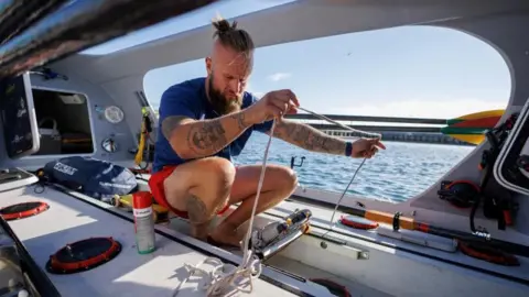 Reuters Lithuanian rower Aurimas Mockus sorts out the ropes on his single-seat boat as he prepares for his journey across the Pacific Ocean