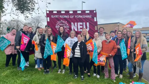 Staff from St Anne's School in Hessle stand on a picket line holding banners and flags