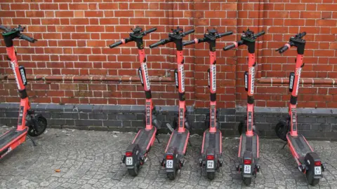 Getty Images Red electric scooters parked in a line on the pavement in Bristol, England