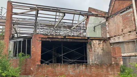 Part of the Life Factory building mid reconstruction with no roof and large holes in the side of the wall.