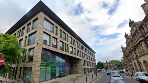 The front of the Wakefield Council building with brown and beige bricks and green windows.