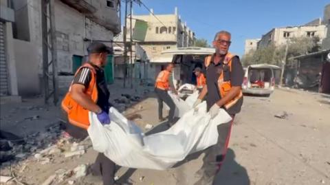 Gazan rescue workers lift body bags into a van