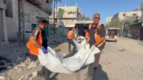 BBC Gazan rescue workers lift body bags into a van