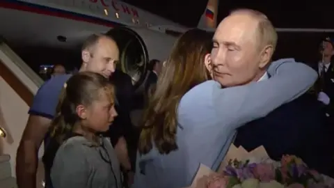 Getty Images Russian President Vladimir Putin (R) welcomes prisoners released following the swap deal at Vnukovo International Airport in Moscow