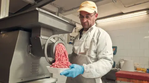 Getty Images Man feeds meat into grinder