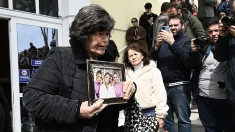 Getty Images A relative holds a victim's picture at the "Gaipolis" conference venue at the University campus in Larissa
