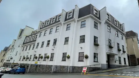 A corner view of a four story white building. 