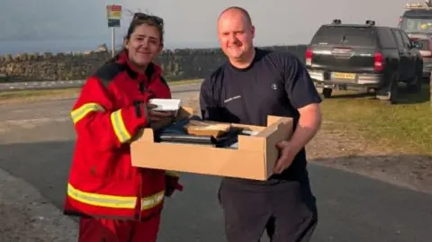 Micklehurst Cricket Club Firefighter receives supplies from Micklehurst Cricket Club.