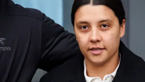 Sam Kerr leaving court in a suit