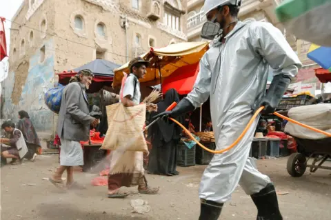 Reuters A worker sprays disinfectant in rebel-controlled Sanaa, Yemen (28 April 2020)