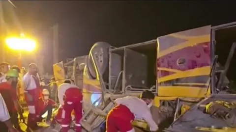 Emergency workers rescue collapsed bus after crash in Iran's Yazd province. Image provided from Irinn, Iranian news agency.