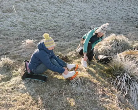 Harry George Hall Skaters lace up their skates on the frozen grass before taking to the ice