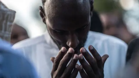 Getty Images A man prays at the burial of Abdalla Mohamed Dahir and Feisal Ahmed on January 16, 2018