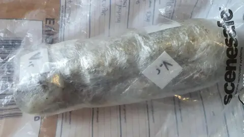 Sussex Police A large clump of items, possibly drugs and mobile phones, wrapped together in cling film. The parcel is pictured within a police evidence bag.