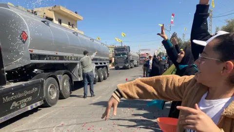 Women throw flower petals at lorries brining Iranian fuel from Syria into Lebanon, in the village of al-Ain (16 September 2021)