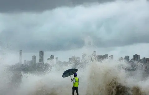 Francis Mascarenhas / Reuters A construction worker watches as waves crash against the shore