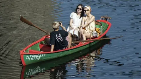 PA Media People in a row a boat enjoy the hot weather on the River Nidd in Knaresborough, North Yorkshire