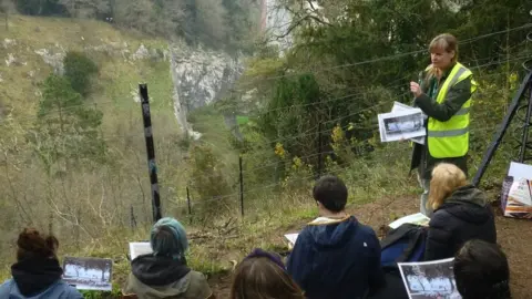 Avon Gorge and Downs Wildlife Project A group of young people sitting on grass learning about green space in Bristol with trees surrounding them