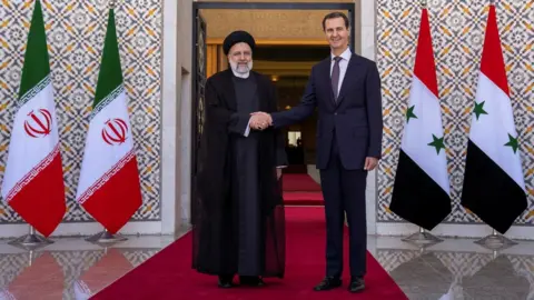 Reuters Iranian President Ebrahim Raisi (L) shakes hands with Syrian President Bashar al-Assad (R) during a visit to Damascus, Syria (3 May 2023)