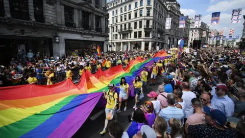 ANDY RAIN Participants carry a giant Rainbow flag as tens of thousands of people attend the annual London Pride Parade in