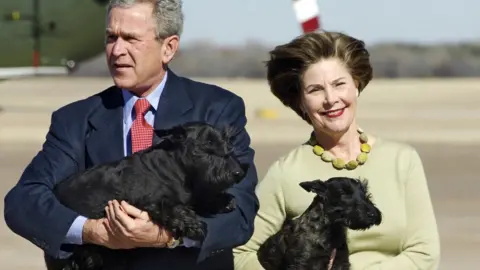 Getty Images US President George W. Bush carries his dog Barney as Fist Lady Laura Bush holds Miss Beazley in 2005