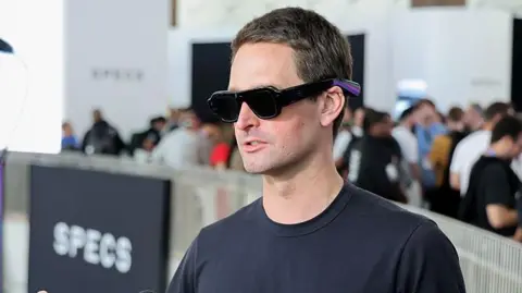 Getty Images Head and shoulders photo of a man wearing chunky black sunglasses and a black t-shirt