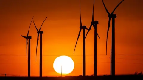 Getty Images A Texas wind farm BP later sold, with turbines seen in silhouette against a red sky and setting sun 