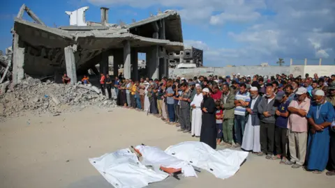 reuters mourning people pray next to the bodies of palestinians killed in israeli strikes, during their funeral, amid the israel-hamas conflict, in khan younis in the southern gaza strip, october 2, 2024.