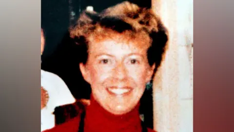 An old photo of Janice Cartwright-Gilbert is wearing a red polo-neck jumper.