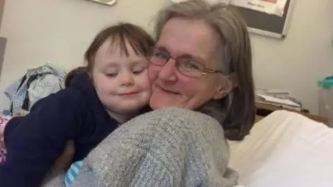 Handout Julie hugging Maisy on a hospital bed