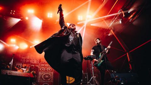 Skindred on stage at Bristol Sounds 2024 with performers illuminated by spotlights behind them