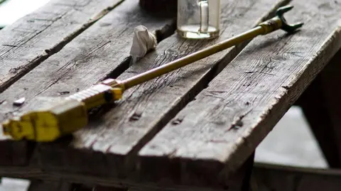 Roee Shpernik/Wiki Commons Stock image of an electric cattle prod lying on a wooden bench, with a glass mug in the background