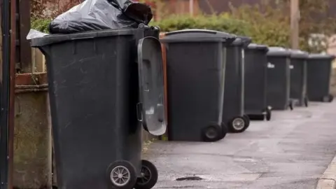 BBC An overflowing wheelie bin 