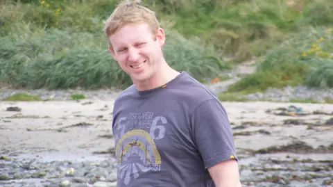 Supplied Paul Scott on the beach wearing a purple t-shirt