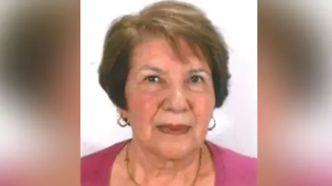 West Mercia Police A woman with a pink top and a necklace is looking at the camera. She has brown hair and the background behind her is white.