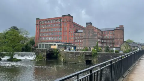 Large Georgian orange bricked building sitting infront of a body of water