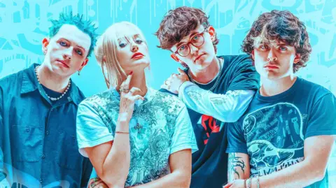 South Arcade pose for a band picture. Cody has spiky green hair, Harmony has blonde hair tied up, Ollie has a brown mullet and red rimmed glasses, Harry has a brown punk moptop.